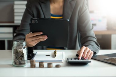 Bütçe kavramını hesaplamak için sürahi bardağa ve hesap makinesine madeni paralar koyarak tasarruf ediyoruz.
