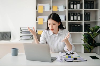 Woman who is tired and overthinking from working with tablet and laptop at office.