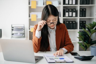 Woman who is tired and overthinking from working with tablet and laptop at office.