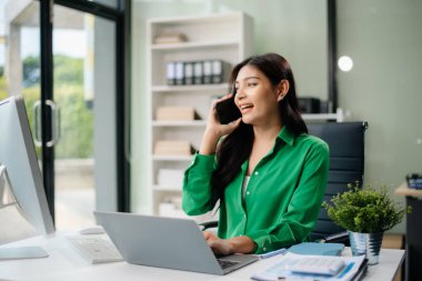  Güzel Asyalı kadın çalıştığı yerde bilgisayarını ve tabletini kullanıyor. İşine odaklan..