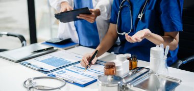 Doctors and nurses review medical paperwork and prescriptions in a professional healthcare setting. Hospital staff teamwork, patient care