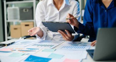 Ofis masasında akıllı telefon ve hesap makinesi olan iş belgeleri dijital tablet ve sosyal ağ diyagramı olan grafik işleri ve ofiste çalışan iki iş arkadaşı