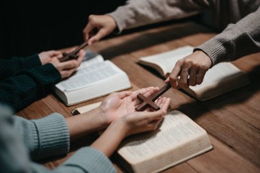 Bir grup Hıristiyan birlikte oturup odalarında açık İncil sayfaları olan ahşap bir masanın etrafında dua ediyorlar. Allah 'ın lütuf ve ihsanını dileyin.
