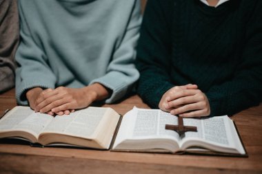 Bir grup Hıristiyan birlikte oturup odalarında açık İncil sayfaları olan ahşap bir masanın etrafında dua ediyorlar. Allah 'ın lütuf ve ihsanını dileyin.