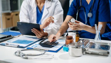Doctors and nurses review medical paperwork and prescriptions in a professional healthcare setting. Hospital staff teamwork, patient care