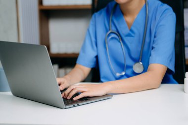 Tıbbi veriler, reçete yönetimi ve dijital sağlık çözümleri için akıllı telefon ve laptop kullanan mavi önlüklü profesyonel hemşire.