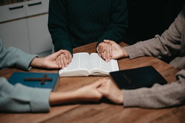 Bir grup Hıristiyan birlikte oturup odalarında açık İncil sayfaları olan ahşap bir masanın etrafında dua ediyorlar. Allah 'ın lütuf ve ihsanını dileyin.