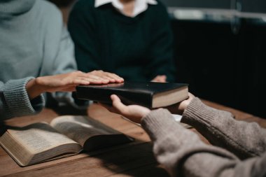 Bir grup Hıristiyan birlikte oturup odalarında açık İncil sayfaları olan ahşap bir masanın etrafında dua ediyorlar. Allah 'ın lütuf ve ihsanını dileyin.
