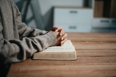 Bir grup Hıristiyan birlikte oturup odalarında açık İncil sayfaları olan ahşap bir masanın etrafında dua ediyorlar. Allah 'ın lütuf ve ihsanını dileyin.