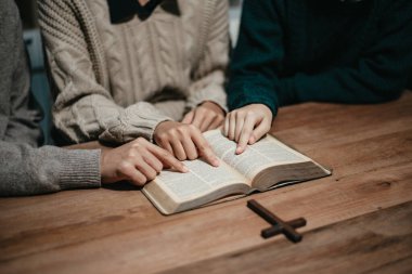 Bir grup Hıristiyan birlikte oturup odalarında açık İncil sayfaları olan ahşap bir masanın etrafında dua ediyorlar. Allah 'ın lütuf ve ihsanını dileyin.