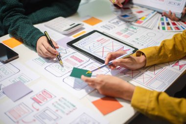 UI müteahhitlerinin projelerini dizüstü bilgisayar, akıllı telefon ve dijital tablet ile beyin fırtınası yaparken görüntülerini kapatın. Yaratıcı dijital geliştirme ajansı.