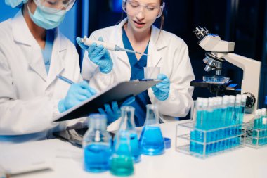 Modern Medical Research Laboratory Portrait of Two Scientists Working, Using Digital Tablet, Analyzing Samples, Talking. for Medicine, Biotechnology
