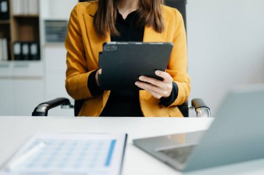business documents on office table with smart phone and digital tablet and graph financial and woman working at offic