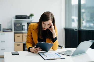 Frustrated young businesswoman working on a laptop computer sitting at his working place in offic