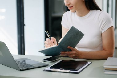 Üniversite kütüphanesinde okuyan, bilgisayarını, tabletini ve kulaklığını kullanan, video sohbeti yapan çekici, mutlu genç bir öğrenci..