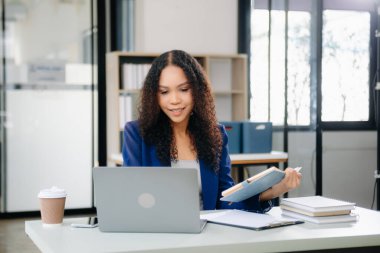 Kendine güvenen iş uzmanı, gülümseyen, dizüstü bilgisayarda yazan ve dijital tableti yaratıcı ofiste tutan çekici genç bir kadın..