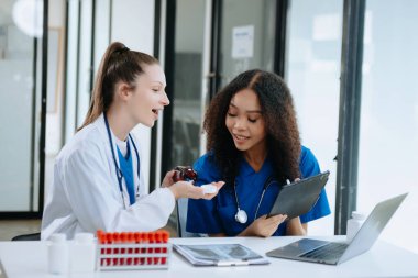  Doktor, profesyonel baş hemşire ya da cerrahla konuşuyor. Dijital tablet bilgisayar kullanıyorlar. Muhtelif sağlık uzmanları test sonuçlarını hastanede masasında tartışıyor. 