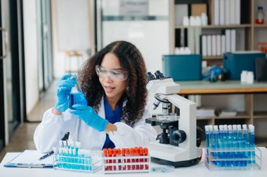 Bir tıp laboratuvarında araştırma yapan genç bilim adamları, ön plandaki bir araştırmacı, tıp laboratuarında bir mikroskop kullanıyor..  