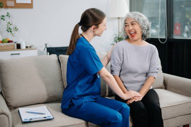 Doctors explain the use of medication to patients. Medical doctor holing senior patient's hands and comforting her on sofa at home