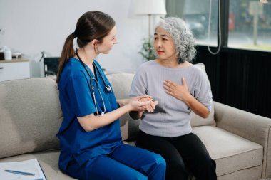 Young nurse helping elderly woman walk in the room, holding his hand, supporting. Treatment and rehabilitation after injury in assisted living facility, senior care