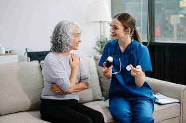 Doctors explain the use of medication to patients. Medical doctor holing senior patient's hands and comforting her on sofa at home