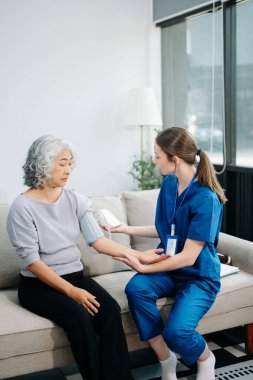 Doctors explain the use of medication to patients. Medical doctor holing senior patient's hands and comforting her on sofa at home