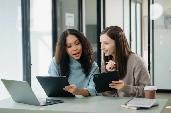 Asyalı iş arkadaşları sunar ve açıklar ve dizüstü bilgisayar ve tablet kullanır. Takım çalışması, finansal pazarlama ekibi, modern ofis odasında otururken