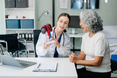 Doctor in white suit take notes while discussing and Asian elderly, man patient who lying on bed with receiving saline solution in hospital or clinic