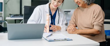 Doctor in white suit take notes while discussing and Asian elderly, man patient who lying on bed with receiving saline solution in hospital or clinic