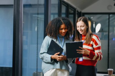 İki iş adamı akıllı telefondan konuşuyor ve ofiste dizüstü bilgisayar kullanıyorlar..
