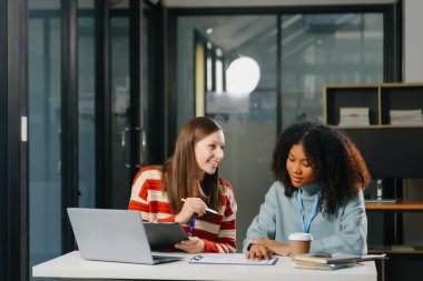 İki iş adamı akıllı telefondan konuşuyor ve ofiste dizüstü bilgisayar kullanıyorlar..