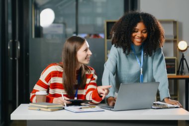 İki iş adamı akıllı telefondan konuşuyor ve ofiste dizüstü bilgisayar kullanıyorlar..