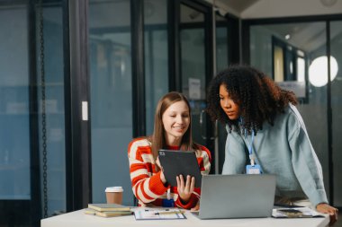 İki iş adamı akıllı telefondan konuşuyor ve ofiste dizüstü bilgisayar kullanıyorlar..