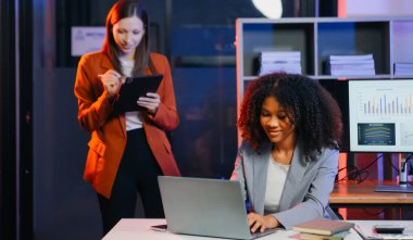 İki iş adamı akıllı telefondan konuşuyor ve ofiste dizüstü bilgisayar kullanıyorlar..