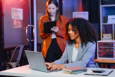 İki iş adamı akıllı telefondan konuşuyor ve ofiste dizüstü bilgisayar kullanıyorlar..