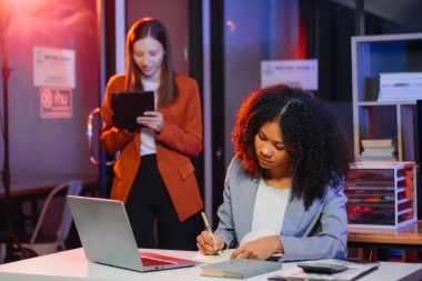 İki iş adamı akıllı telefondan konuşuyor ve ofiste dizüstü bilgisayar kullanıyorlar..