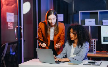 İki iş adamı akıllı telefondan konuşuyor ve ofiste dizüstü bilgisayar kullanıyorlar..