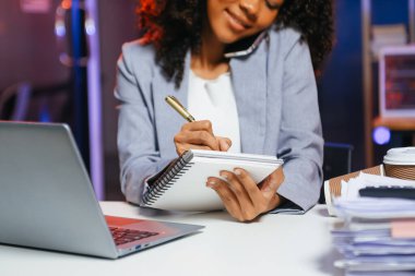 Afrikalı kadın migren ağrısı çekiyor. Ofiste dizüstü bilgisayar ve tablet üzerinde çalışırken aşırı çalışan iş kadını finansör.