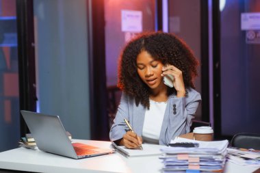 Afrikalı kadın migren ağrısı çekiyor. Ofiste dizüstü bilgisayar ve tablet üzerinde çalışırken aşırı çalışan iş kadını finansör.