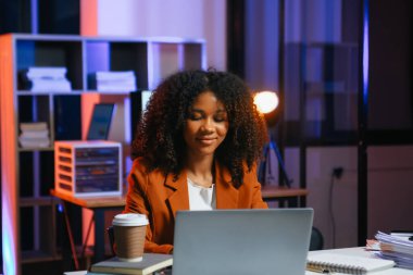 Afrikalı kadın migren ağrısı çekiyor. Ofiste dizüstü bilgisayar ve tablet üzerinde çalışırken aşırı çalışan iş kadını finansör.