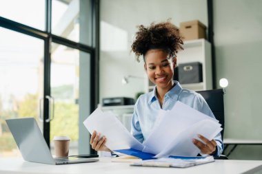 Çalışan not defteri, tablet ve dizüstü bilgisayarla çalışan genç iş kadını akıllı telefon, tablet ve dizüstü bilgisayarla konuşuyor. Video arama vergisi, rapor, muhasebe