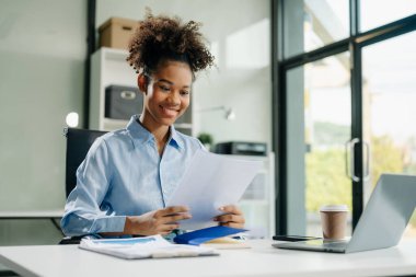 Çalışan not defteri, tablet ve dizüstü bilgisayarla çalışan genç iş kadını akıllı telefon, tablet ve dizüstü bilgisayarla konuşuyor. Video arama vergisi, rapor, muhasebe