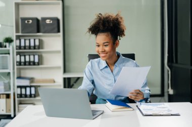 Çalışan not defteri, tablet ve dizüstü bilgisayarla çalışan genç iş kadını akıllı telefon, tablet ve dizüstü bilgisayarla konuşuyor. Video arama vergisi, rapor, muhasebe