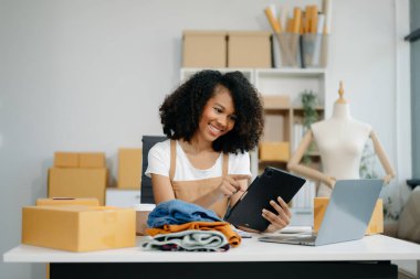 Asian young woman SME working using smartphone or tablet taking receive and checking online purchase shopping order to ,freelance business online concept.