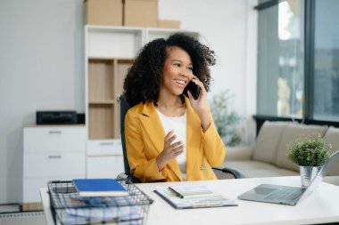 Modern ofiste elinde not defteri ve tabletle gülümseyen kendine güvenen bir kadın.