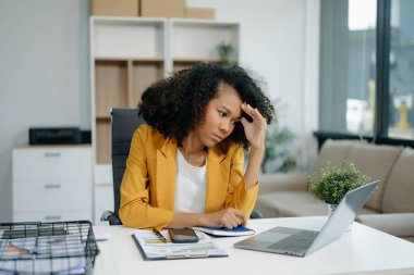 Woman feeling migraine head strain.Overworked businesswoman financier while working on laptop and tablet at office.