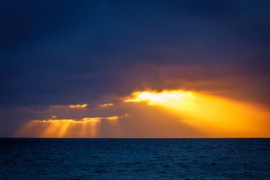 Dramatik gün batımı gökyüzü ve güneş ışınlarıyla denizin üzerindeki bulutlar.