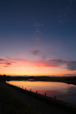 Amble Braid 'den gün batımı Warkworth Kalesi ve Coquet Nehri manzaralı, Northumberland 2025