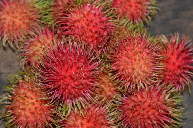 Makro taze rambutan görüntüsü canlı kırmızı deri ve kıllı doku gösteriyor. Egzotik meyve temaları, tropikal gıda görselleri ya da doğal ürün sunumları için mükemmel..