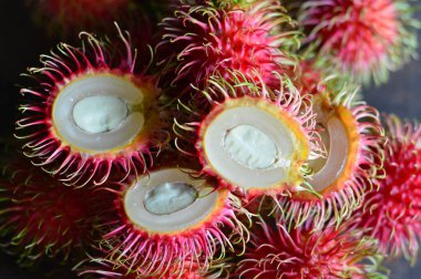 Rambutan meyvesi dikenli kırmızı deri ve yumuşak saçların altını çizer. Sağlıklı gıda reklamları, tropikal pazarlar veya Güneydoğu Asya mutfağı içeriği için ideal.